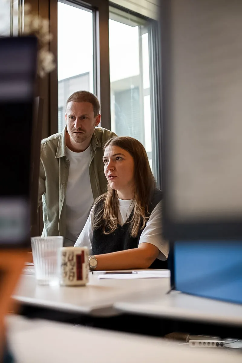 Zwei Sidekicks prüfen gemeinsam am Bildschirm — Human-in-the-Loop.